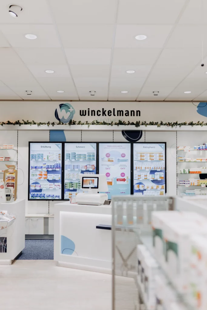 Der Verkaufsraum der Winckelmann Apotheke mit vier digitalen Info-Screens und weihnachtlicher Girlande.