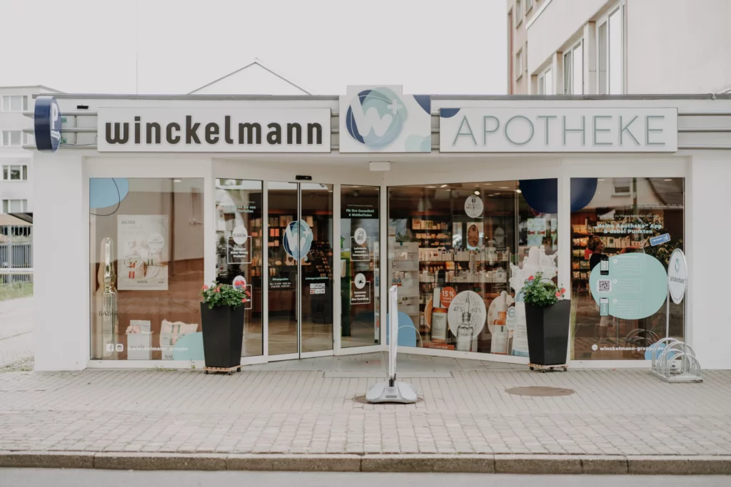 Außenansicht einer Winckelmann Apotheke Stendal mit großen Schaufenstern, Blumenkübeln und Fahrradständern.