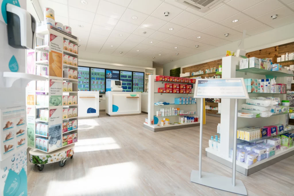 Ein heller Verkaufsraum mit Hygieneartikeln, Aktionsflächen und digitalen Info-Screens im Hintergrund.